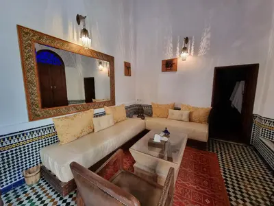 a living room with a couch and a mirror at Riad Le Sucrier de Fès in Fès