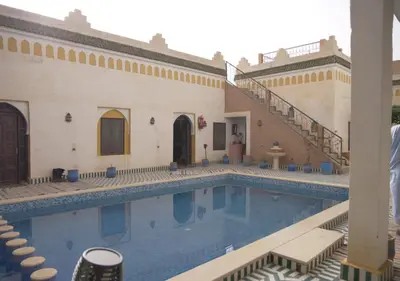 a swimming pool next to a building with stairs at Casa Laman in Merzouga