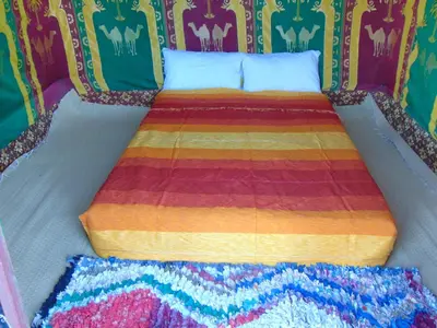 a bed with a colorful comforter in a room at Merzouga Authentic Camps in Merzouga