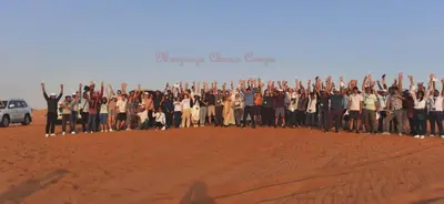 a group of people posing for a picture in the desert at Merzouga Authentic Camps in Merzouga