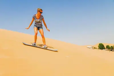 a woman riding a surfboard in the desert at Merzouga Authentic Camps in Merzouga