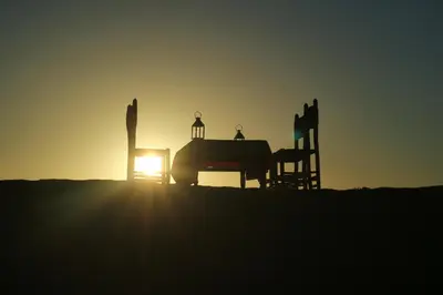 two children sitting on a playground at sunset at Merzouga Authentic Camps in Merzouga