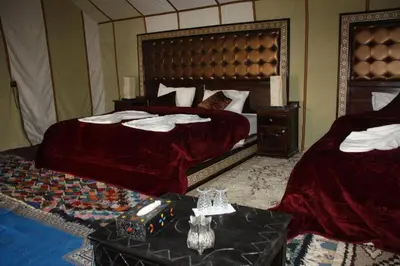 a hotel room with two beds and a table at Sunset Camp Merzouga in Merzouga