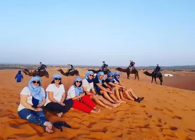 a group of women posing for a picture on the beach at Sunset Camp Merzouga in Merzouga