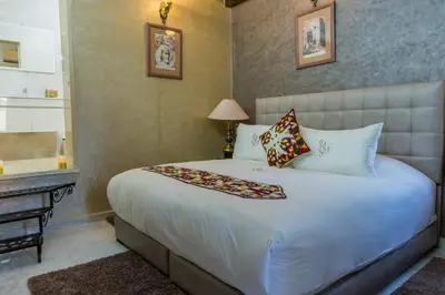 a bedroom with a large white bed and a desk at Riad Sebti Fès in Fès