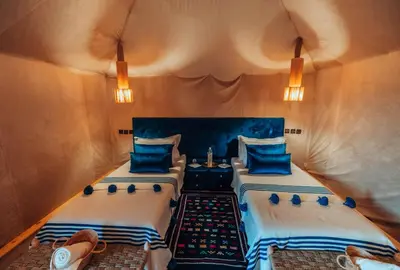 a bedroom with two beds with blue pillows at Royal Nomad Camp in Merzouga