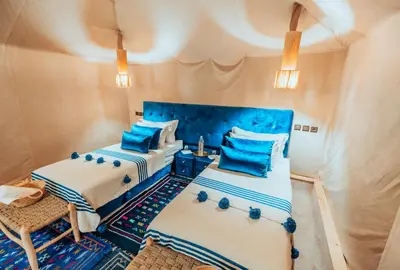 two beds in a room with blue and white at Royal Nomad Camp in Merzouga