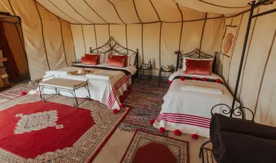 a bedroom with two beds in a tent at Royal Nomad Camp in Merzouga