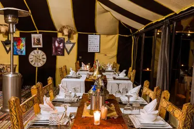 a dining room with tables and chairs and a clock at Royal Nomad Camp in Merzouga