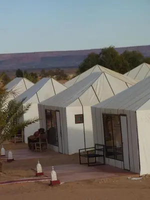 a row of white tents in a field at Nomad Camp Merzouga in Merzouga