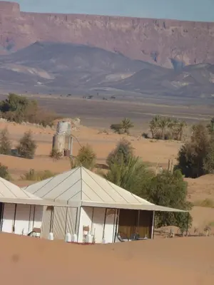 a tent in the desert with a mountain in the background at Nomad Camp Merzouga in Merzouga