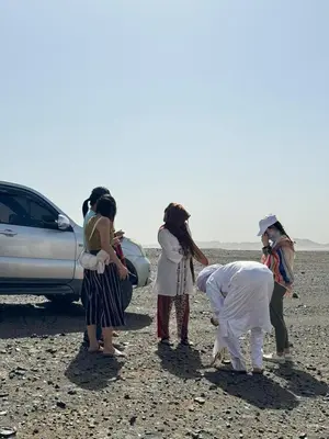 a group of women standing around a car in the desert at Nomad Camp Merzouga in Merzouga