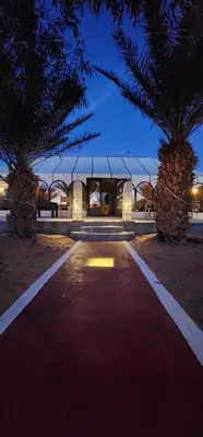 two palm trees in front of a building at night at Nomad Camp Merzouga in Merzouga