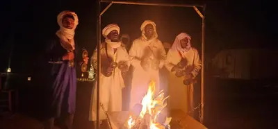 a group of people standing in front of a fire at Nomad Camp Merzouga in Merzouga