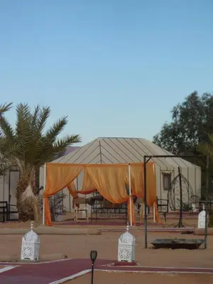 an orange tent in front of a building at Nomad Camp Merzouga in Merzouga