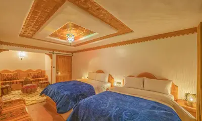 a bedroom with two beds and a ceiling at Hotel Riad Bahammou in Aït Idaïr