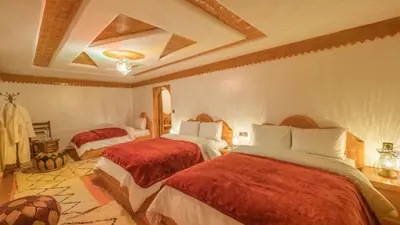 a bedroom with two beds with red comforters at Hotel Riad Bahammou in Aït Idaïr