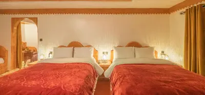 a bedroom with two beds with red and white pillows at Hotel Riad Bahammou in Aït Idaïr