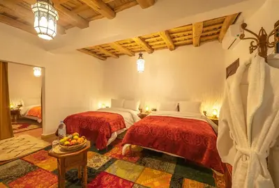 a bedroom with two beds and a table with a bowl of fruit at Hotel Riad Bahammou in Aït Idaïr