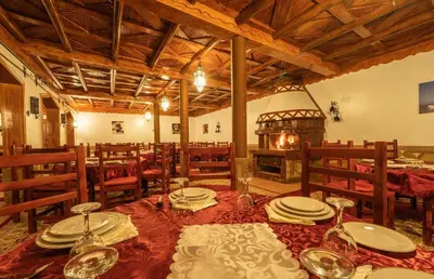 a dining room with a table and a fireplace at Hotel Riad Bahammou in Aït Idaïr