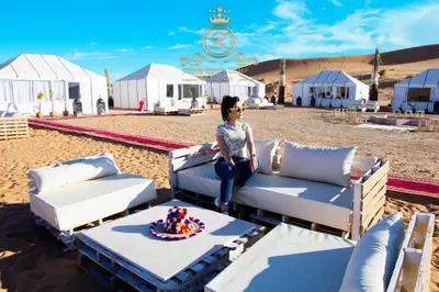 a woman sitting on a couch on the beach at ITRAN ROYAL CAMP in Merzouga