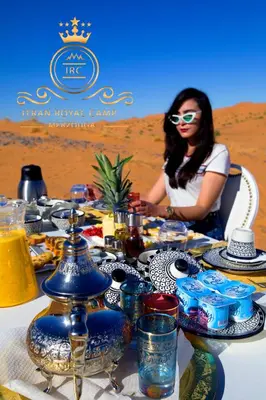 a woman sitting at a table in the desert at ITRAN ROYAL CAMP in Merzouga