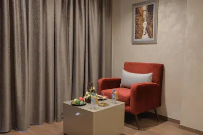 a living room with a red chair and a table at Nour Plazza Hotel in Fès