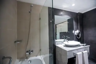 a bathroom with a shower and a sink and a tub at Nour Plazza Hotel in Fès