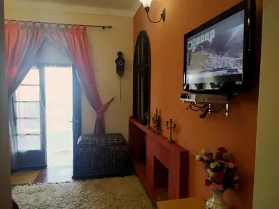 a living room with a flat screen tv on the wall at Maison d'hôtes Jnan Atlas in Sidi Abdalwahad