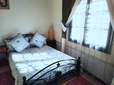 a bedroom with a bed with blue pillows and a window at Maison d'hôtes Jnan Atlas in Sidi Abdalwahad