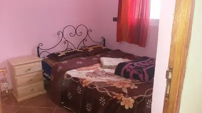 a small bedroom with two beds and a dresser at Merzouga Quiet apart &camels trecking in Merzouga