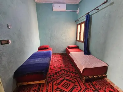 a room with two beds and a carpet at Merzouga Quiet apart &camels trecking in Merzouga
