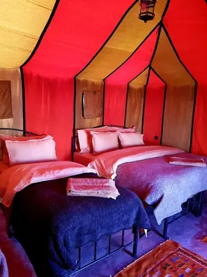 two beds in a room with a red ceiling at Bedouin Desert Camp in Merzouga