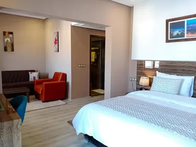 a bedroom with a bed and a living room at Hôtel Atlas Saiss Fès in Fès