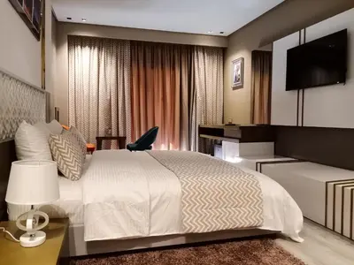 a bedroom with a bed and a desk and a tv at Hôtel Atlas Saiss Fès in Fès