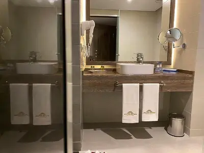 a bathroom with two sinks and two mirrors and towels at Hôtel Atlas Saiss Fès in Fès