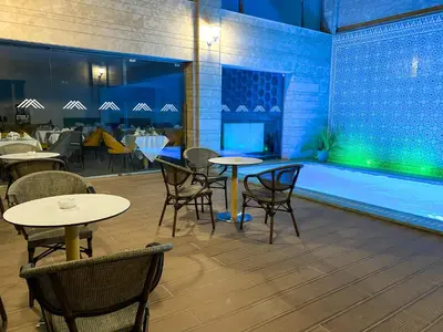 a restaurant with tables and chairs next to a swimming pool at Hôtel Atlas Saiss Fès in Fès