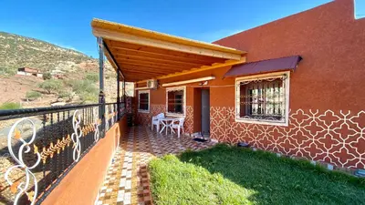 a house with a balcony with a table on the porch at Scenic Lakeview House Near 5-Star Widian Hotel in Bine el Ouidane