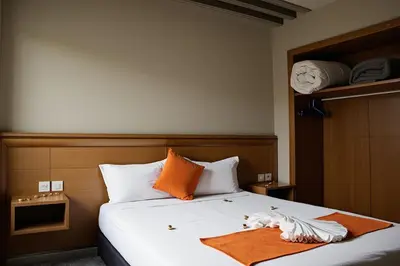 a bedroom with a bed with orange and white pillows at Hotel Golden Flora in Beni Mellal