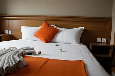 a bed with orange and white pillows and a blanket at Hotel Golden Flora in Beni Mellal