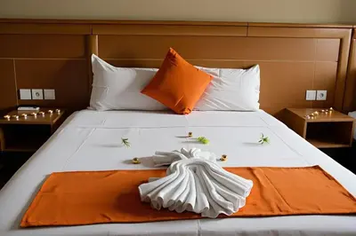 a white bed with an orange and white towel on it at Hotel Golden Flora in Beni Mellal