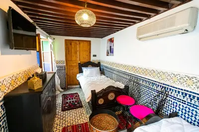 a room with two beds and a tv in it at Palais Riad Chahd Luxury in Fès