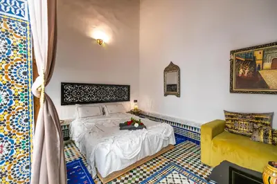 a bedroom with a white bed and a yellow couch at Palais Riad Chahd Luxury in Fès