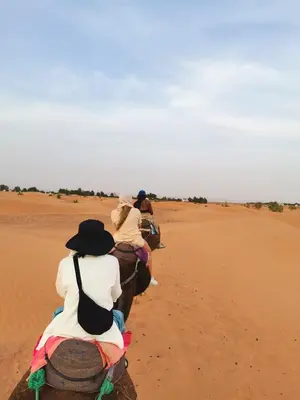 a group of people riding horses in the desert at Jardin Kotori Luxury Camp in Merzouga