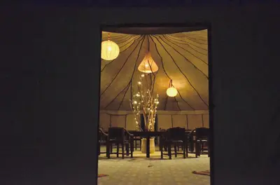 a room with a tent with a table and chairs at Jardin Kotori Luxury Camp in Merzouga