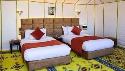a bedroom with two beds with red pillows at Merzouga Desert Luxury Camp in Merzouga