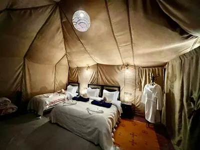 a bedroom with two beds in a tent at Merzouga Desert Luxury Camp in Merzouga
