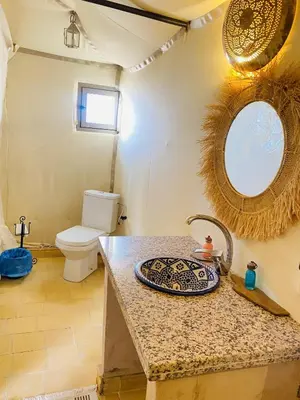 a bathroom with a sink and a toilet and a mirror at Amskou Camp in Merzouga