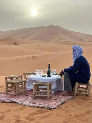 a man sitting at a table in the desert at Amskou Camp in Merzouga