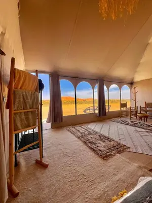 a room with large windows and a chair in a room at Amskou Camp in Merzouga